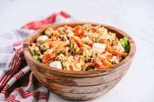 A big wooden salad bowl filled with a delicious roasted antipasto salad.
