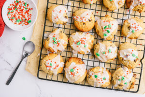 Peanut butter and chocolate chip ricotta cookies on a rack next to a spoon and a small bowl with sprinkles.