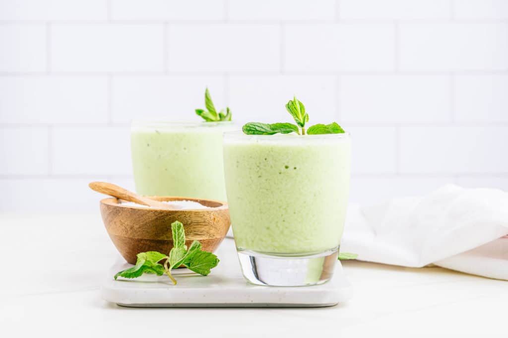 Minty yogurt smoothie in a small glass, adorned with fresh mint leaves.
