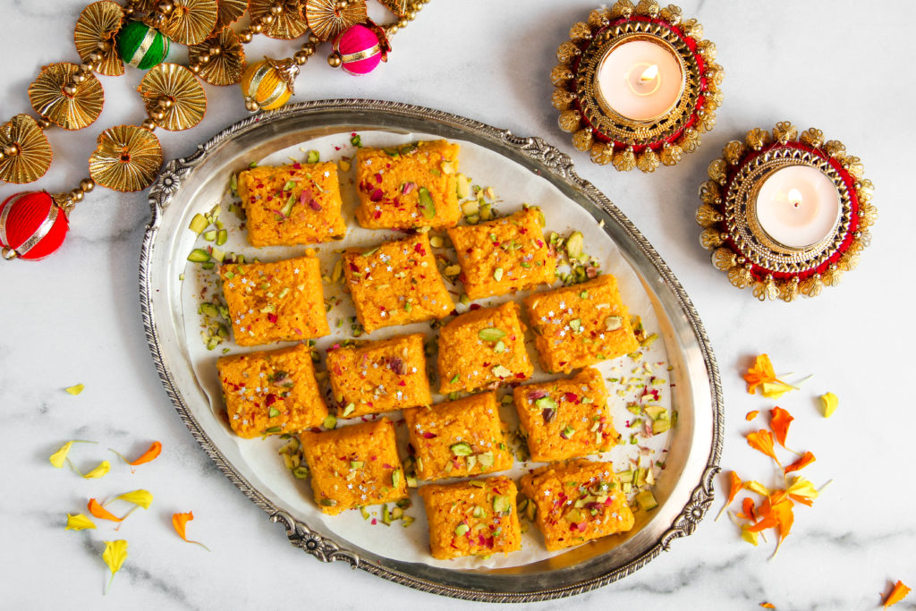 Delicious Indian mango kalakand squares on a silver plate, over a marble table.