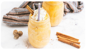 Smooth and creamy pumpkin pie in a mason jar with cinnamon sticks on the side.