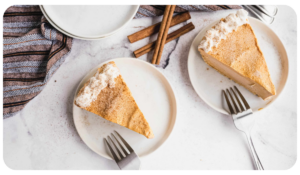 Two white plates, each with a piece of delicious pumpkin praline cheesecake.