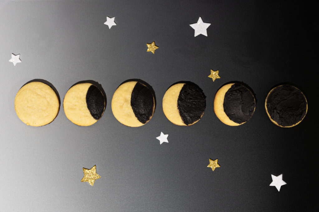 A row of delicious yellow eclipse cookies with black icing of differing sizes to represent the eclipse.