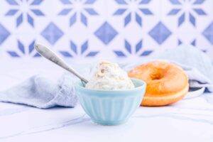 Un donut servido junto a un tazón pequeño de helado de café.