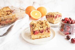 Un pequeño trozo de tarta de naranja y arándanos servido en un plato.