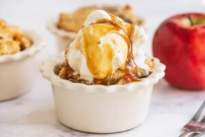 Postre de manzana y caramelo servido en un plato pequeño de cerámica redondo.